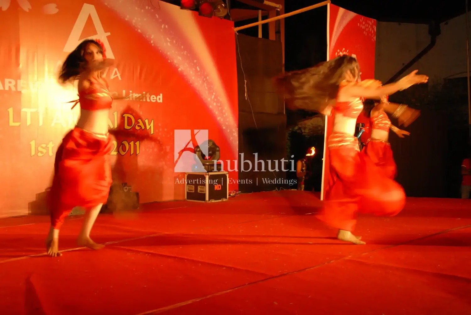 Man and woman speaking on stage at night with blue lighting